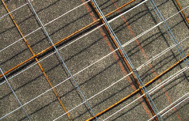 Typical welded wire fabric a tight grid of galvanized utility fencing, with the roll of fencing material tied to the flat sheets of welded wire.