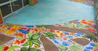 Concrete overlay in sea blue by Butterfield Color guides visitors to the entrance of an after school program in San Antonio, Texas.