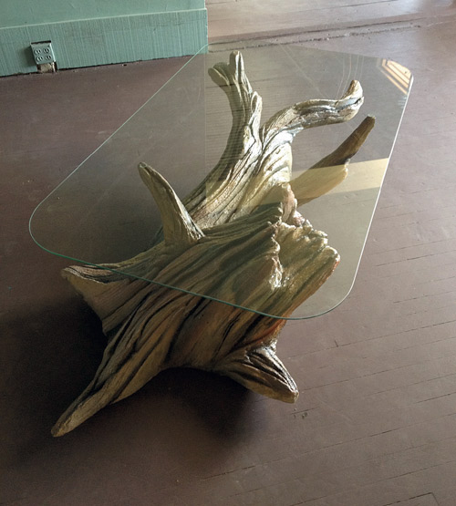 Faux wood sculpted concrete coffee table with glass top.