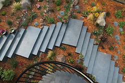 Alcantar color hardener in Platinum was used to tint the poolside coping, the countertops in the small kitchen, and gray elements of the deck. This hardener was also used for the cheek walls that flank the steps, as well as the bench seat walls, which are capped with Ipe, an attractive hardwood from Brazil. The concrete wall lodged into the hillside was also stuccoed with Platinum. 