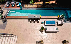 Two concrete countertops  one on the upper deck from which a waterfall cascades into the pool, the other on the coping with sitting stools underwater  were finished with Scofields Classic Gray color hardener, as were the stairs and other surfaces.