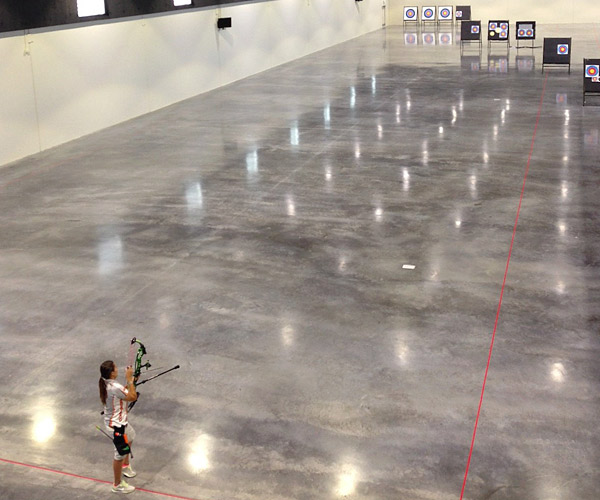 Polished Concrete Archery Range used polished concrete as it's surface of choice in the U.S. Olympic Training Center. Girl shooting arrow over polished concrete prior to the U.S. Olympic games.