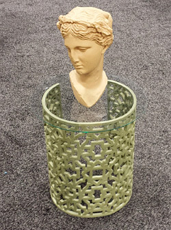 GFRC end table using a lattice mold then bending the mold to create a semi-circular look. Glass top with 3-D concrete sculpture of a head.