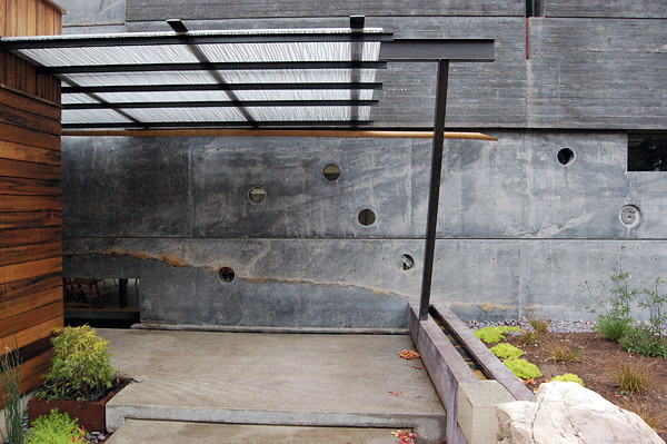 In addition to integrally colored concrete, FuTung Chengs House 6 (note the 6 at the far right) in Menlo Park, California, features a water sluice on the right. Water runs toward the homes wall and drops over the edge into a channel running left and into a pond. The entrys canopy is made of carbonate embedded with twigs. The assembled elements reflect Chengs design philosophy of integrating architectural and structural elements. Photo by Matthew Millman Photography