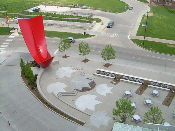 Near a large urban state park, the likeness of a northern cardinal, Indianas state bird, perches in a tulip poplar, Indianas state tree. Some of the leaves form a stage in the plaza.