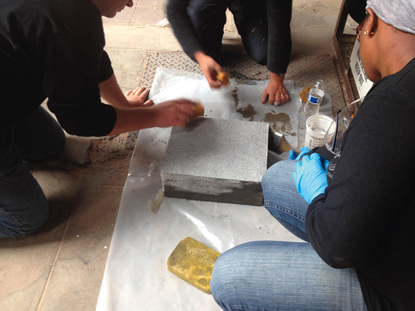 students color sampling cast concrete - Students color a sample that was cast using the texture skin they helped to make. The samples will be used when they pour footings for the wall panels.