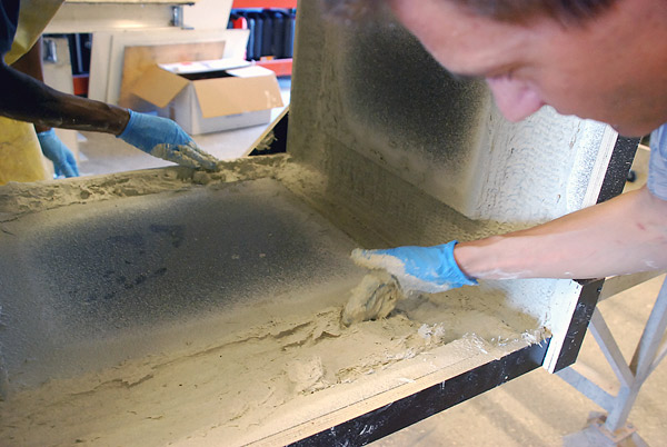 Molding a patio table with GFRC backer coat that is high-fiber and placed by hand.