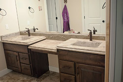 Tiered bathroom vanity light tan with dual integral sinks.