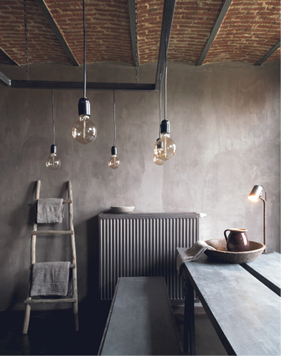 Gray concrete table with retro lights hanging from ceiling.