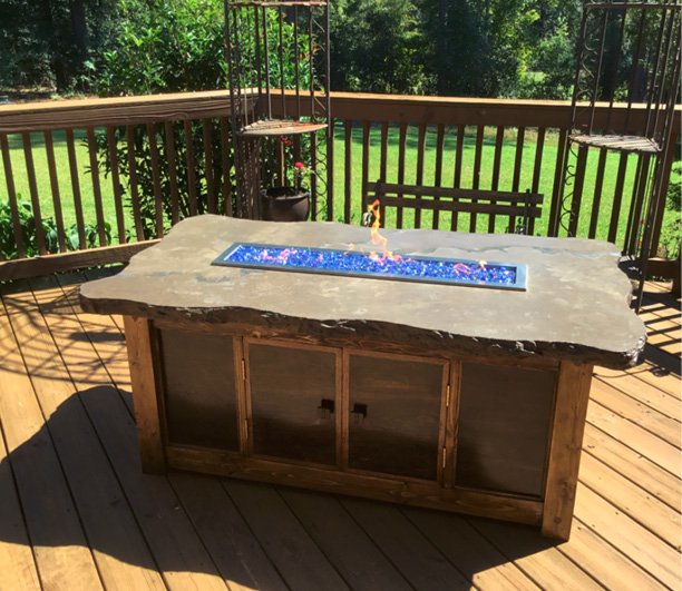 Outdoor fire table made with a concrete countertop. Features a row of blue glass aggregate with flame tube. Photos courtesy of Concrete In-Counters concrete countertop firepit