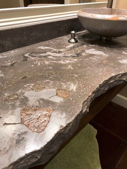 Concrete Countertop in a bathroom with leaf impressions and a broken edging. Concrete vessel sink. Photos courtesy of Concrete In-Counters