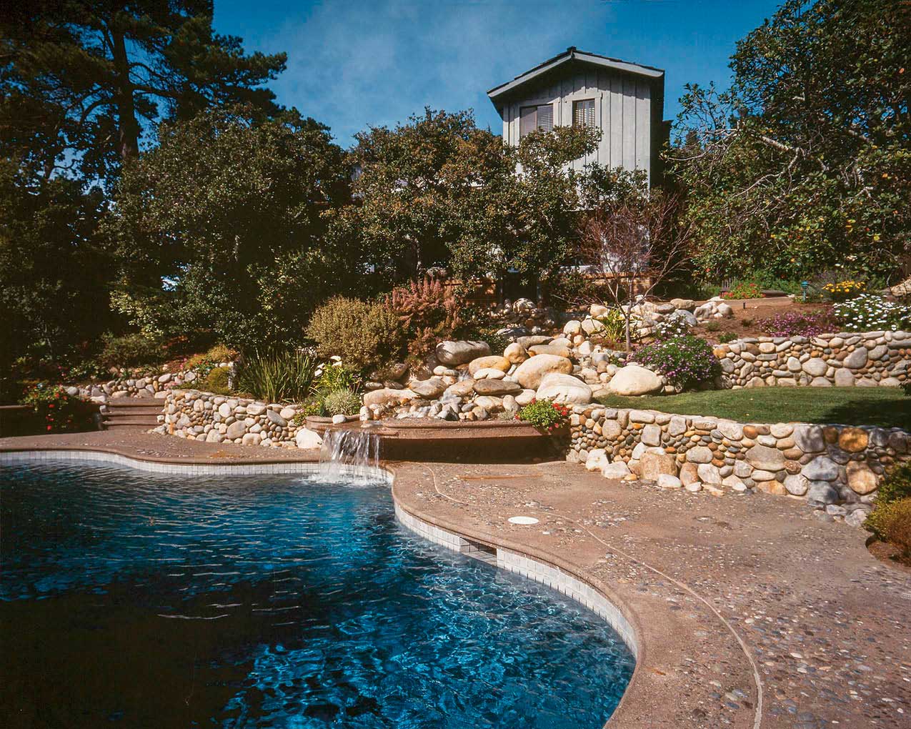 Aggregates take center stage in this pool setting in Carmel, California. River rocks ranging in size from 3 feet to 1/8 inch in diameter create a cliffside/waterfall feature, while natural rock aggregate sculpted and rounded by water creates a streambed effect on the pool deck, with sand washes and clusters of rock. The concretes tan integral color harmonizes with the aggregate. Photos courtesy of Tom Ralston Concrete