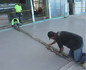 The crew uses chisels and a 2-by-4 as a straight edge to make an initial cut.