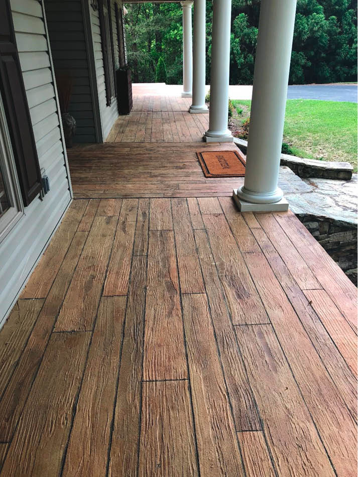 This front porch had a concrete surface to begin with and was rejuvenated with an overlay colored and sculpted to look like wood planks.