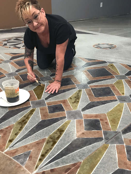 Lee Ann Harris works on the intricate floor using stain and brushes.