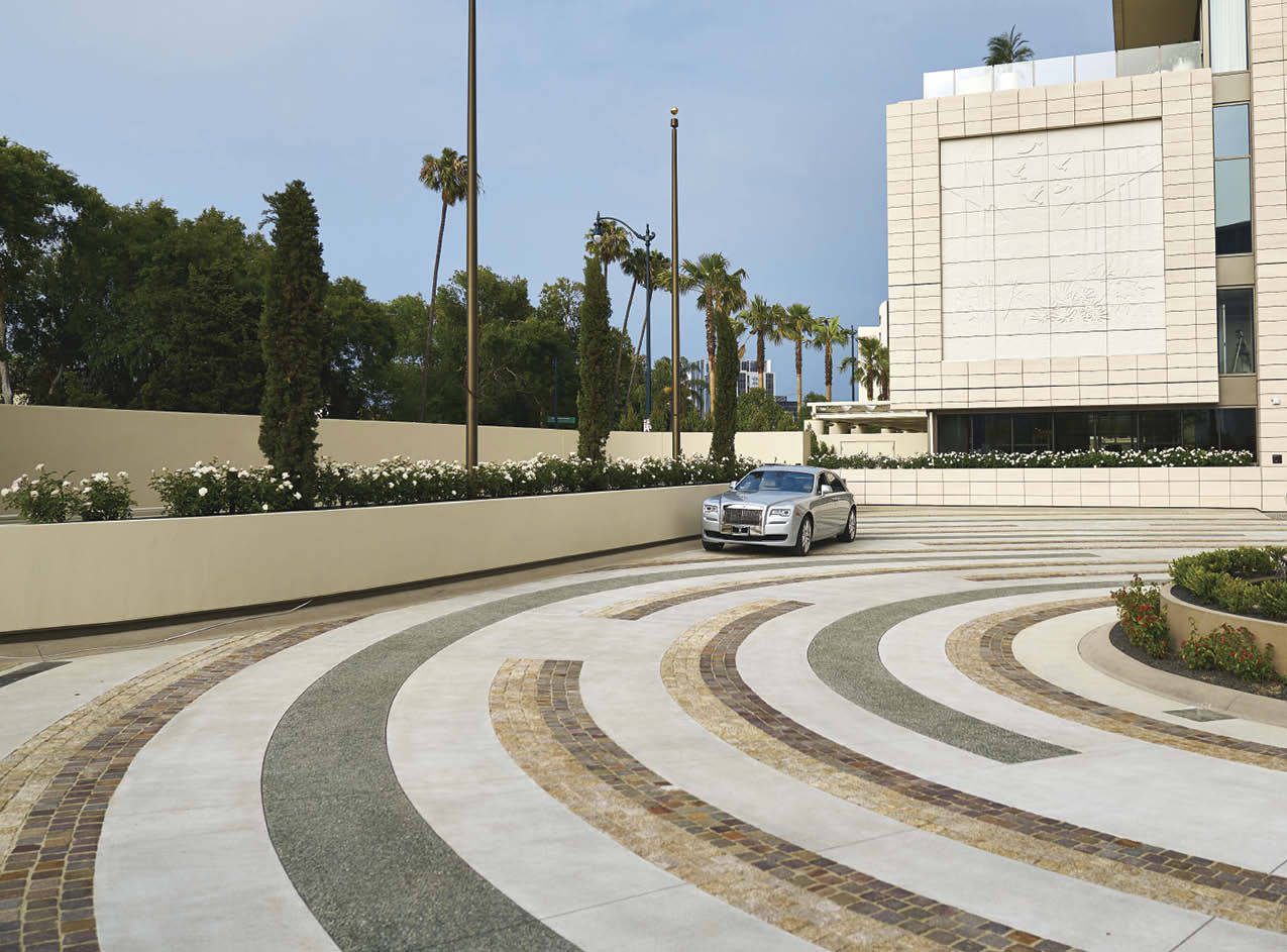 A car on a driveway in front of a hotel with circular stained design.