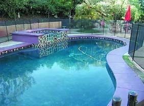 Glistening blue pool water with bluish purple concrete edging with tile.