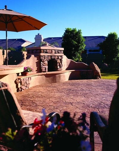 Large outdoor concrete fire place with vertical carved concrete stones is surrounded by flagstone stamped concrete patio. Photographs courtesy of Progressive Concrete Works