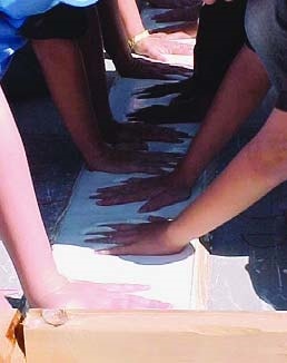 Children pressing hands a mold to later have concrete form made from the hand prints.