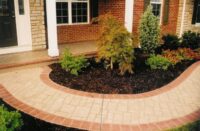 Stenciled concrete pathway leads to entryway and has a red colored border.