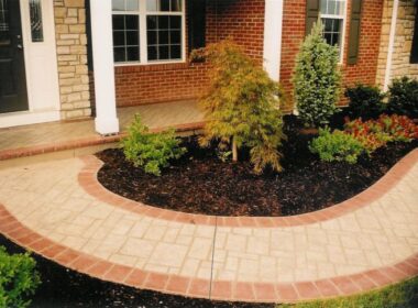 Stenciled concrete pathway leads to entryway and has a red colored border.