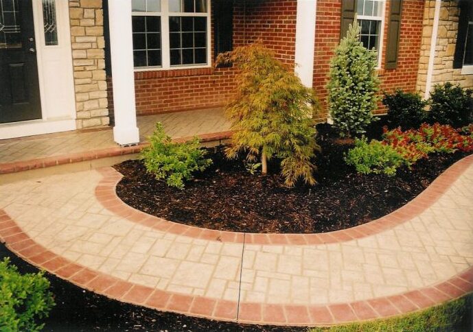 Stenciled concrete pathway leads to entryway and has a red colored border.