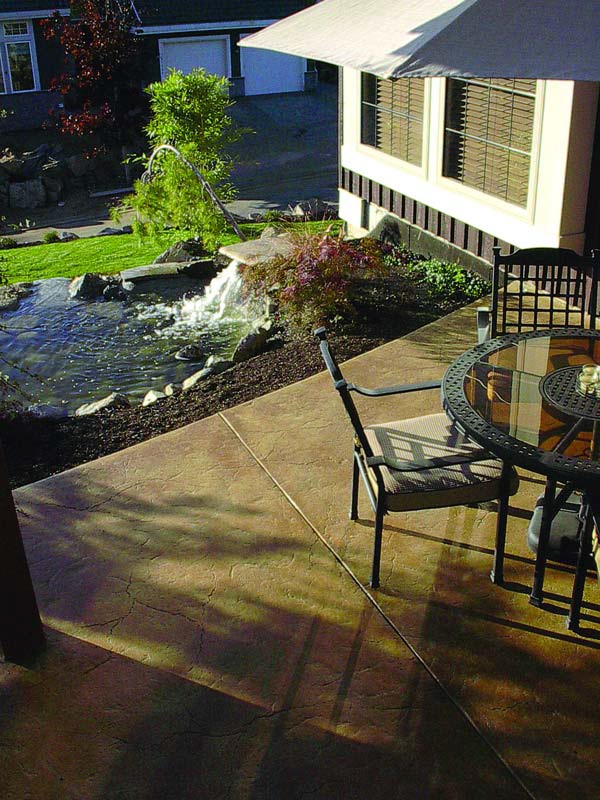 Tumbling water feature next to a textured concrete patio.