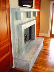 Ready to be stained concrete fireplace surround and mantel look fantastic in this wood paneled living room space.