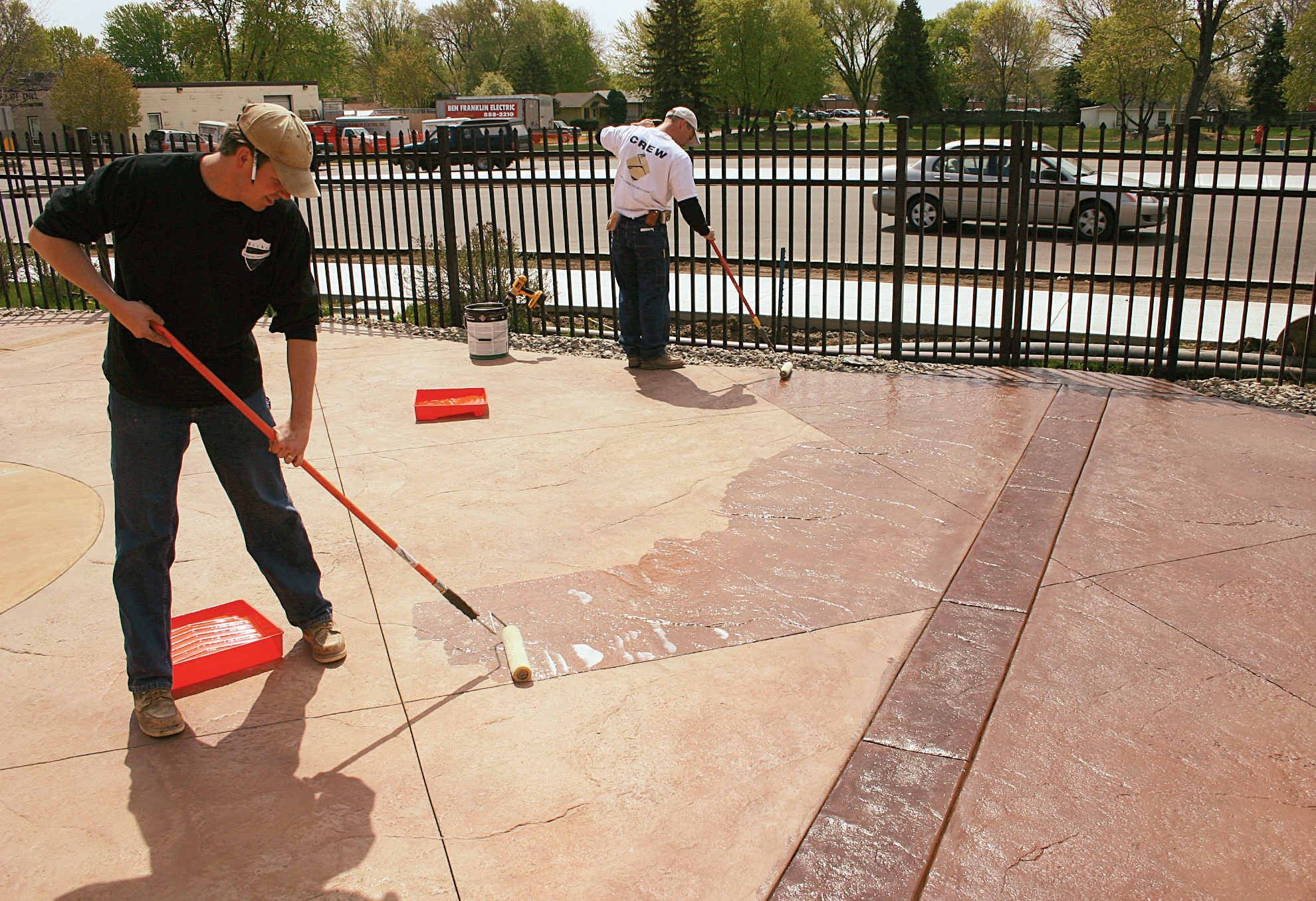 Two people applying sealer with rollers