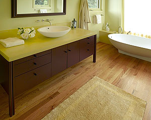 Concrete vanity in yellow on a brown dresser.
