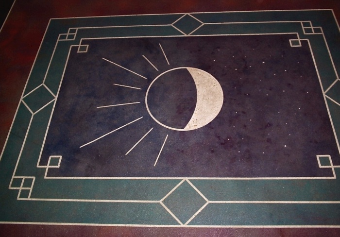 an intricate stain pattern on concrete with a moon and a sun interpretation