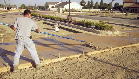 A wood bull float is used to work color into the surface.