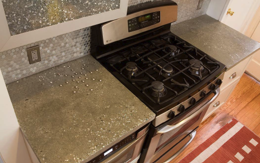 A 1/2-inch thick countertop made with integral color and recycled glass aggregate. The inlaid trivet is made out of stainless steel bolts.