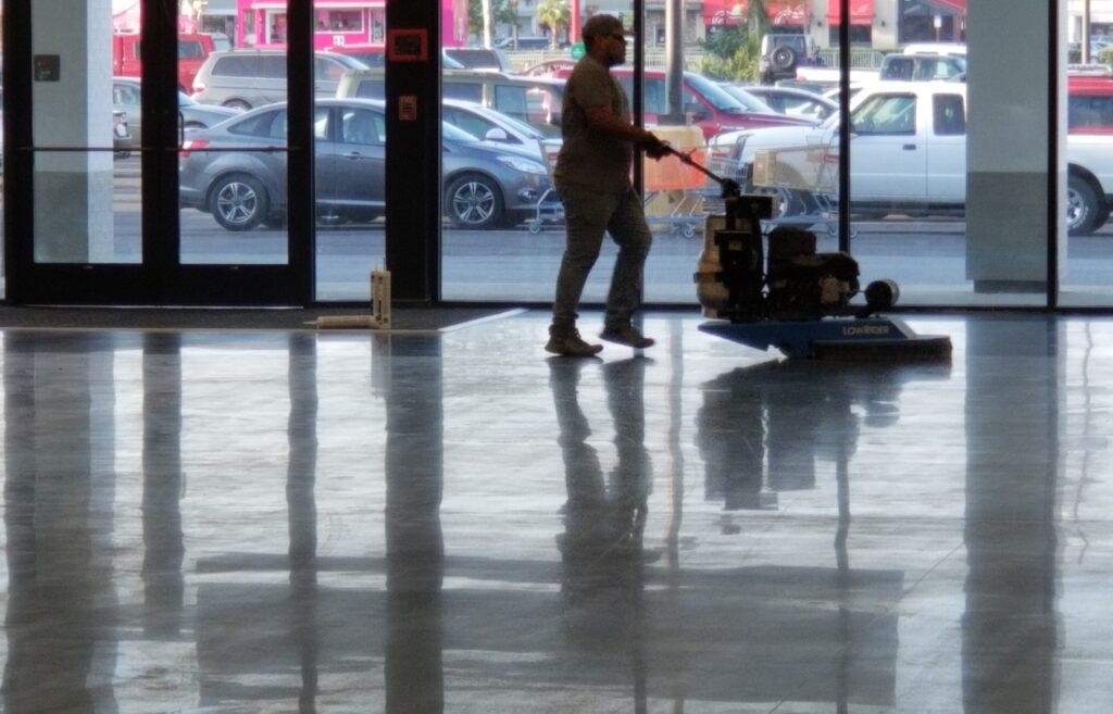 A contractor on a shiny polished floor with a burnisher
