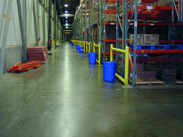 A warehouse with a concrete floor and shelving lining walls.