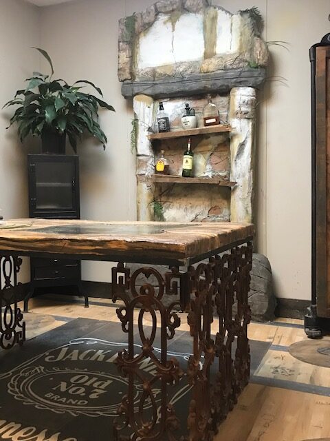 A home office that has a concrete countertop and a concrete bookshelf. The floor looks like a Jack Daniels whiskey barrel.