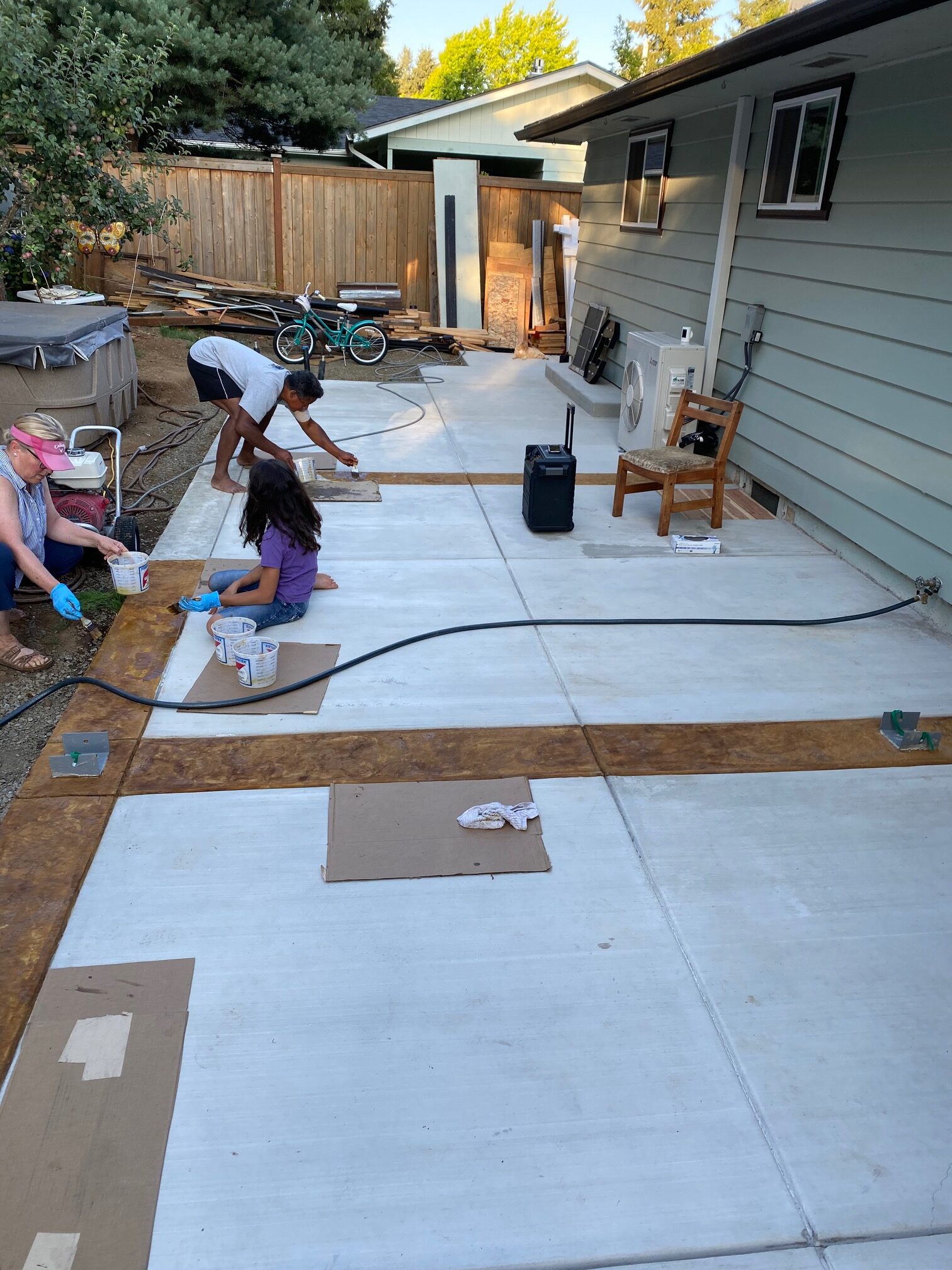 the homeowners staining and texturing the borders of the concrete patio