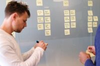 a man in front of a chalkboard with notes and post-its