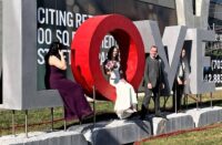 A bride sitting in the O of a LOVE sculpture made of concrete