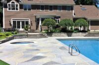 A pool deck finished with Renu-Krete products in front of a brown home