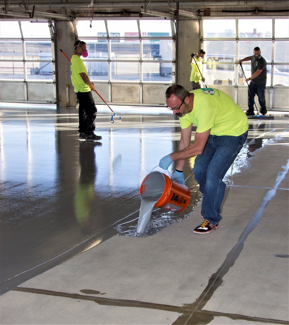 pouring a pigmented moisture mitigator by Laticrete onto the concrete floor