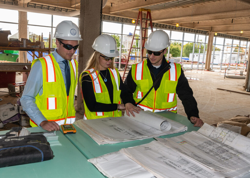 A group of students with blueprints on a job site.