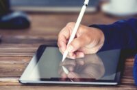 A person signing their digital signature on a tablet.