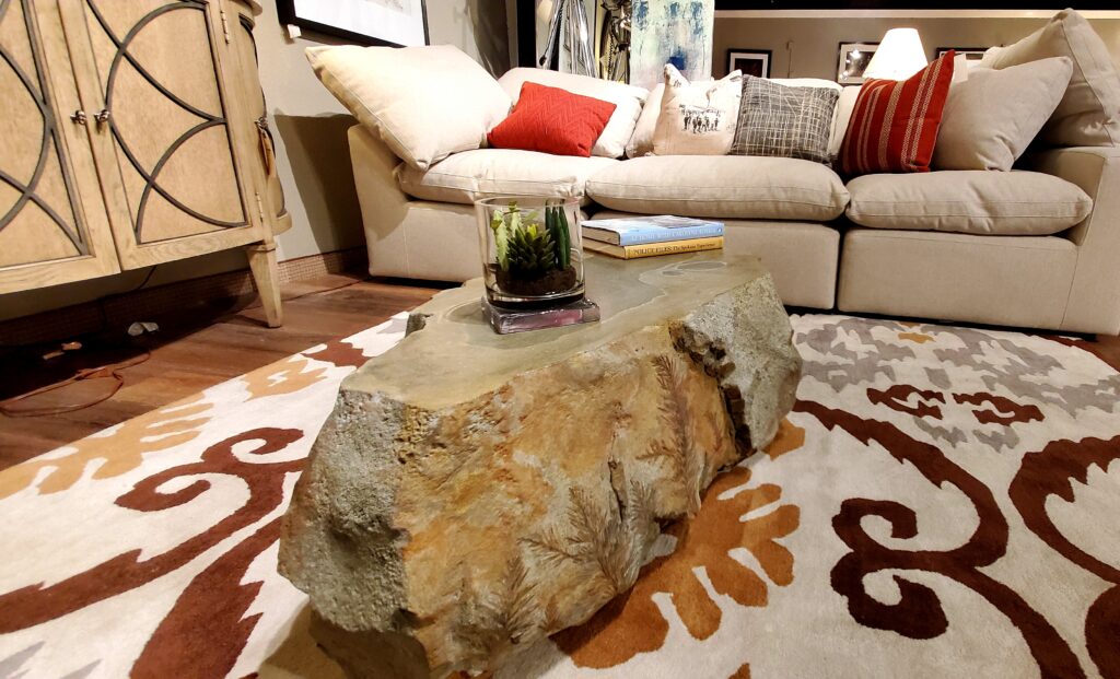 Carved concrete coffee table on a mutli-colored area rug.