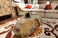 Carved concrete coffee table on a mutli-colored area rug.