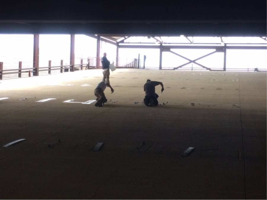 Miracote parking garage restoration - Carbon fiber strapping and sticking placement along girders.