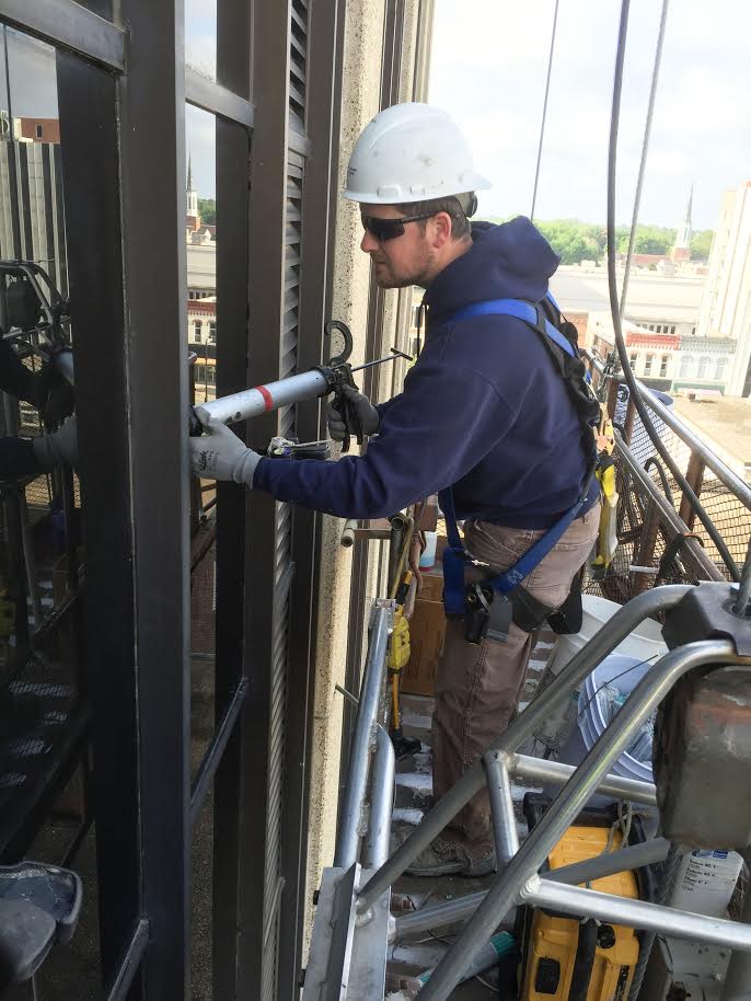 Caulking a window in a high-rise.