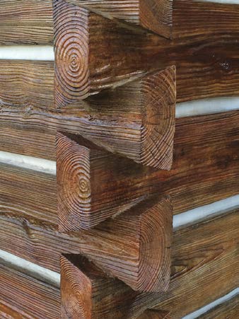 Interlocking concrete logs to create a durable log cabin look that withstands weather.