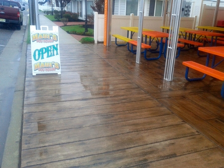 Open sign hangs out on the faux wood concrete sidewalk