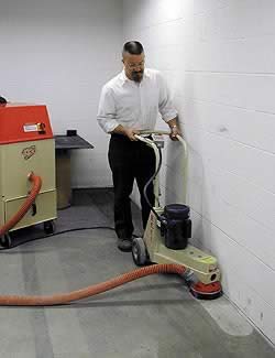 Fancy man in white button up shirt doing surface preparation with a walk behind edge grinder.